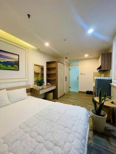 a bedroom with a large white bed and a kitchen at Sentosa- Coco in Dien Ban