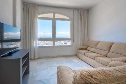 ein Wohnzimmer mit einem Sofa und einem großen Fenster in der Unterkunft Apartamento El Puerto Bahía in Tarifa