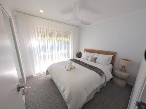 a bedroom with a bed with a teddy bear on it at Villa Salina - 150m to One Mile Beach in Forster