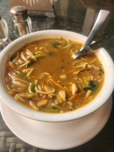 a bowl of noodle soup with a spoon in it at The Gypsy Soul Mukteshwar in Mukteshwar
