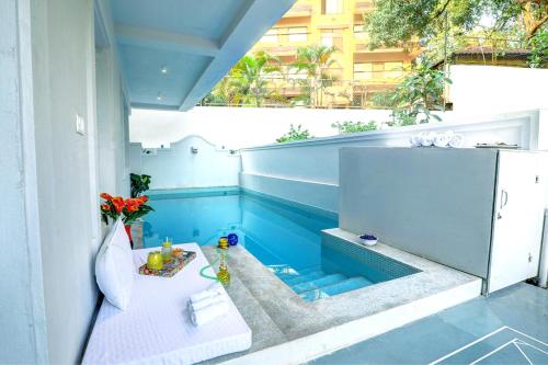 a swimming pool with a table on a balcony at Four Letter Word - 3BHK Private Pool Villa, North Goa in Baga