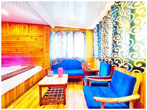 a room with a bed and two chairs and a table at Hotel Lake Naini View - Restaurant &Free Wifi Available - Luxury Collection of Hotels with Spacious Room - Best Lake View Hotel In Nainital in Nainital