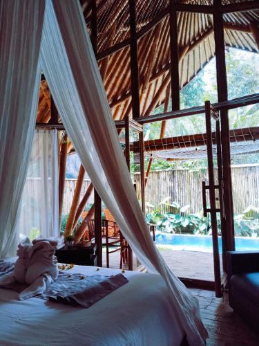 a bedroom with a bed with a mosquito net at Hidden Bamboo Village in Selat