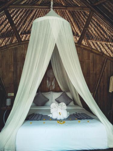 a bedroom with a bed with white drapes at Hidden Bamboo Village in Selat