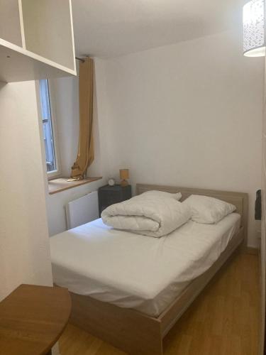 une chambre avec un lit avec des draps blancs et une fenêtre dans l'établissement appartement T2 RDC, à Ax-les-Thermes