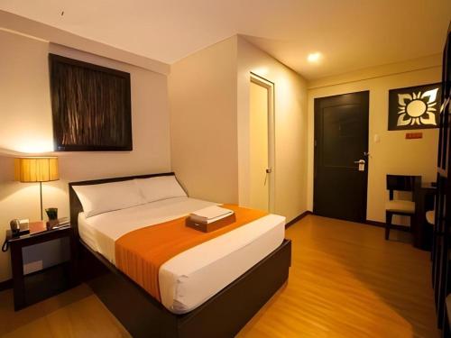 a bedroom with a bed and a table and a door at L Square Hotel in Tarlac
