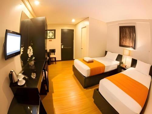 a hotel room with two beds and a flat screen tv at L Square Hotel in Tarlac