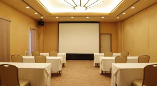 a conference room with white tables and chairs and a screen at Ako Park Hotel in Ako