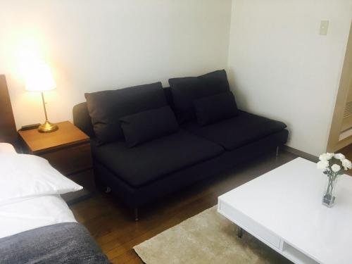 a living room with a black couch and a table at Apartment in Narita 120 in Narita