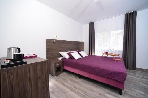 sypialnia z łóżkiem z fioletową pościelą i oknem w obiekcie Villa Jodłowa 6 w Kołobrzegu