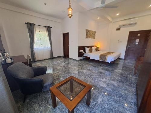 a bedroom with a bed and a chair and a table at Mirage Kandyan Heights in Kandy