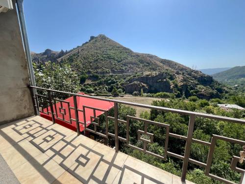 a red bench on a balcony with a view of a mountain at Kirch Hotel & Restaurant in Goris