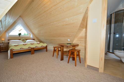 a attic room with a bed and a table and a sink at Sykowny Biały Dunajec in Zakopane