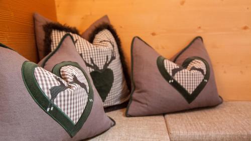 three pillows with hearts on them on a bed at Haus Schönblick - wunderbare Zentrumslage in Alpbach