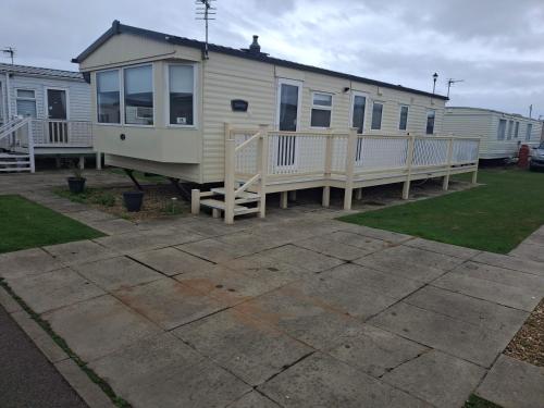 a mobile home with a porch and a deck at 3-Bed Caravan Sleeps 8 Pool & Beach in Chapel Saint Leonards