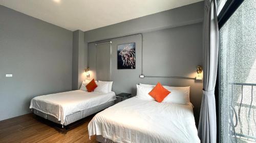 a bedroom with two beds with white sheets and orange pillows at Taitung Sun forest in Taitung City