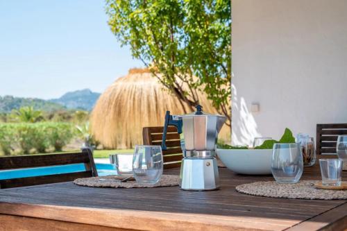 a table with a coffee maker and glasses on it at Mallorquin Oasis with natural pool 5min from the beach in Port de Pollensa
