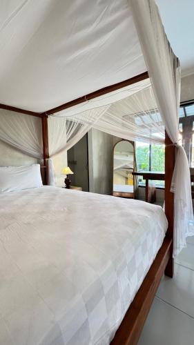 a bedroom with a large white bed with a canopy at Vila Billy II in Munggu