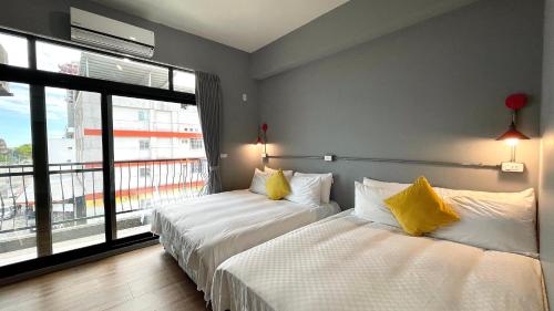 two beds in a room with a large window at Taitung Sun forest in Taitung City