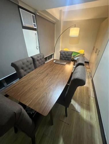 a conference room with a wooden table with chairs and a laptop at Staycation at Eastbay in Manila