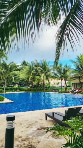 a swimming pool with a bench and palm trees at Staycation at Eastbay in Manila
