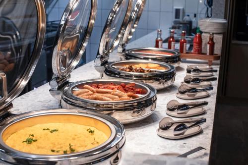 a buffet with several pans of food on a table at Holiday Inn Melbourne Bourke Street Mall by IHG in Melbourne