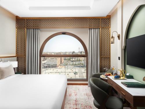 a hotel room with a bed and a large window at Elaf Taiba Hotel in Al Madinah