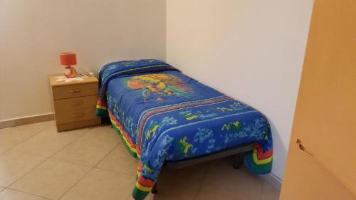 a small bed with a blue comforter and a night stand at B&B RoMa Atella in Atella