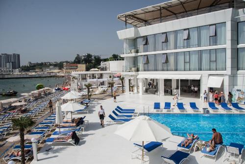 uma piscina com cadeiras azuis e brancas e um edifício em Boutique Hotel Portofino em Odessa