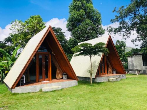 two triangular shaped houses with a tree in the yard at Segara Healing Bali Glamping With Hot Spring in Kubupenlokan