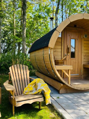 a wooden cabin with a chair and a wooden hobbit house at Bed & Breakfast Voor De Wind in Slootdorp