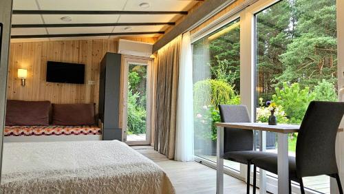 ein Schlafzimmer mit Bett, Tisch und Fernseher in der Unterkunft Nemirsetos kopos in Palanga