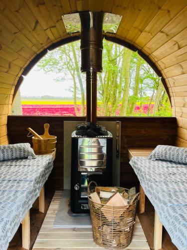 a wood fired stove in a tiny house with a window at Bed & Breakfast Voor De Wind in Slootdorp