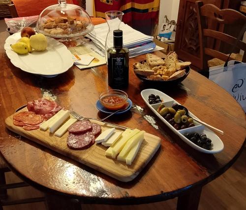 a table with cheese and meats and a bottle of wine at Agriturismo la casa degli amici in Cossignano