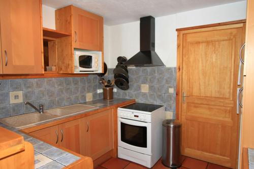 a kitchen with wooden cabinets and a white stove top oven at Le Troll Hameau des Chazals Nevache Hautes Alpes in Névache