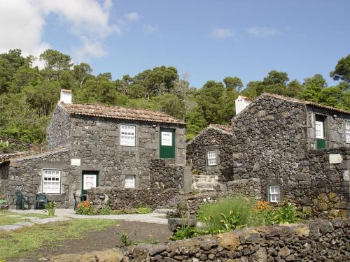 an old stone house with white windows and green shutters at Casas de Campo HousesInPico in Prainha de Baixo