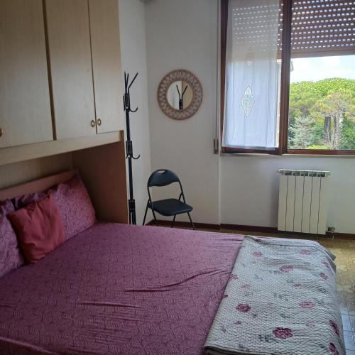 a bedroom with a pink bed and a chair in it at Grande e luminoso appartamento in Lido di Classe