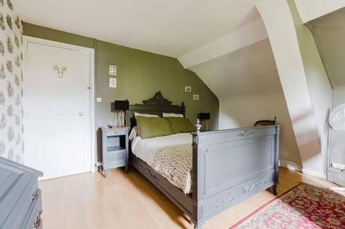 a bedroom with a bed and a green wall at La chaumière du Tordoir in Les Rues-des-Vignes