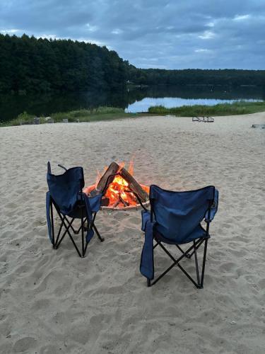 two chairs sitting next to a campfire on a beach at Ośrodek Wypoczynkowy Sosenka in Załom
