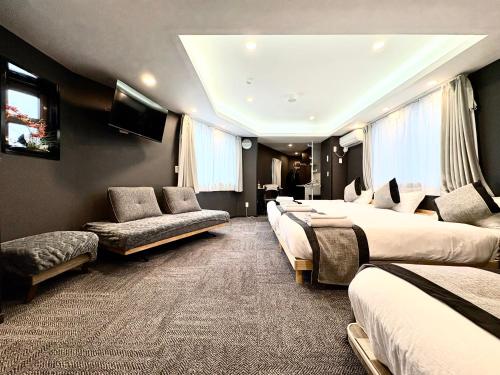 a hotel room with four beds and a couch at Oji正和ビル in Tokyo