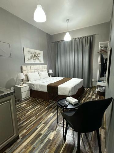 a bedroom with a bed and a table and a chair at Arabian Hotel Apartments in Ajman 
