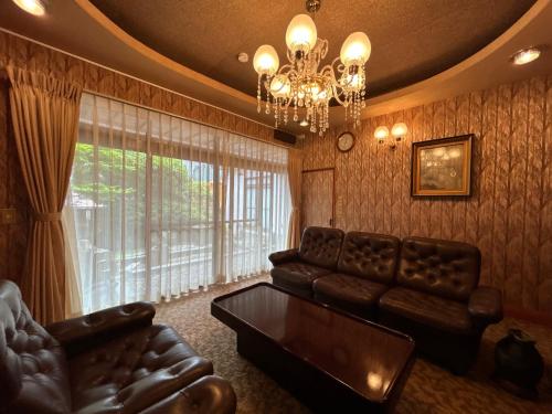 a living room with a couch and a chandelier at Guesthouse Okuwa in Yurihonjo
