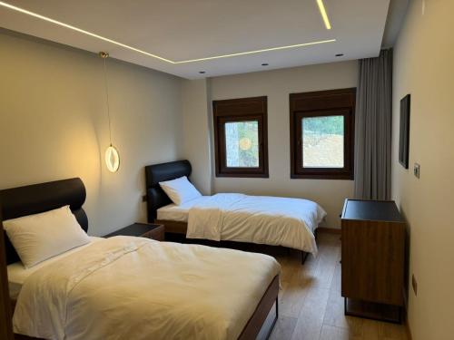 a hotel room with two beds and two windows at بيوت رفال Refal Homes in Ardeşen