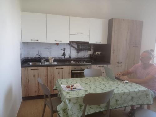 un homme assis à une table de cuisine avec un ordinateur portable dans l'établissement Tra cielo e mare, à Fiumicino