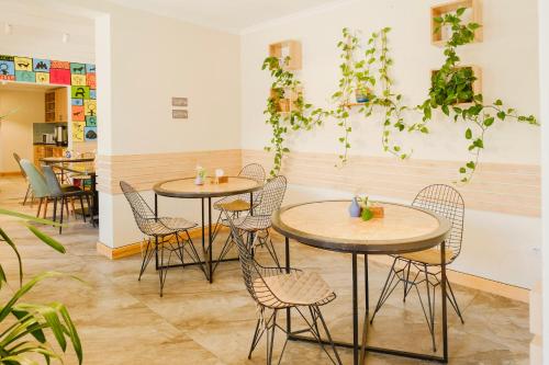 a restaurant with tables and chairs and plants on the wall at People Guest House in Bishkek