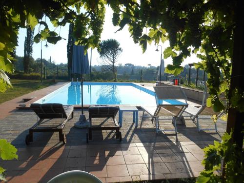 a pool with chairs and a table and an umbrella at Agriturismo La Pineta in Fucecchio