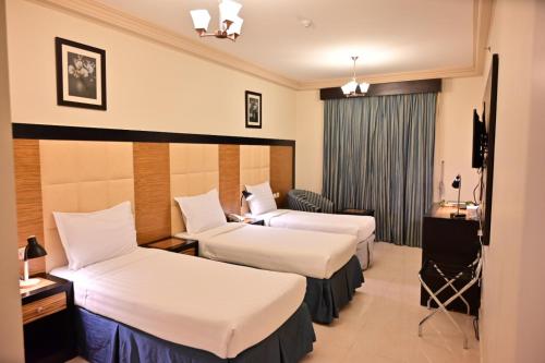 a hotel room with two beds and a desk at ديار المشاعر الهداية الفندقية Diyaralmashaer Al-Hadiyah Hotel in Makkah