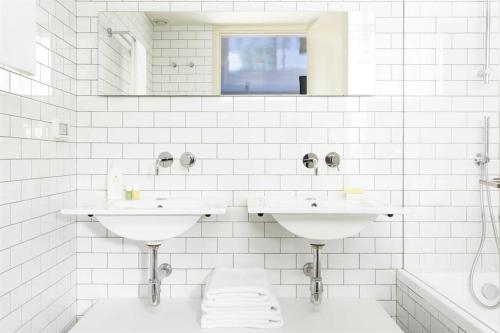 a white bathroom with two sinks and a mirror at Florentin House - By HOMY in Tel Aviv