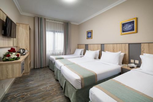 a hotel room with two beds and a television at Emaar Taiba Hotel in Medina