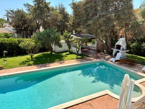 una grande piscina in un cortile alberato di Villa Meigama - Porto Giunco a Notteri